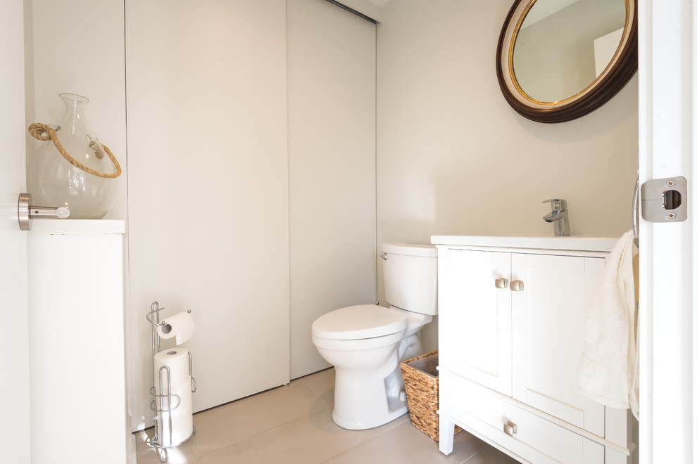 Klassisk inredning av ett mellanstort toalett, med möbel-liknande, vita skåp, en toalettstol med separat cisternkåpa, grå kakel, porslinskakel, grå väggar, klinkergolv i porslin, ett integrerad handfat och bänkskiva i akrylsten