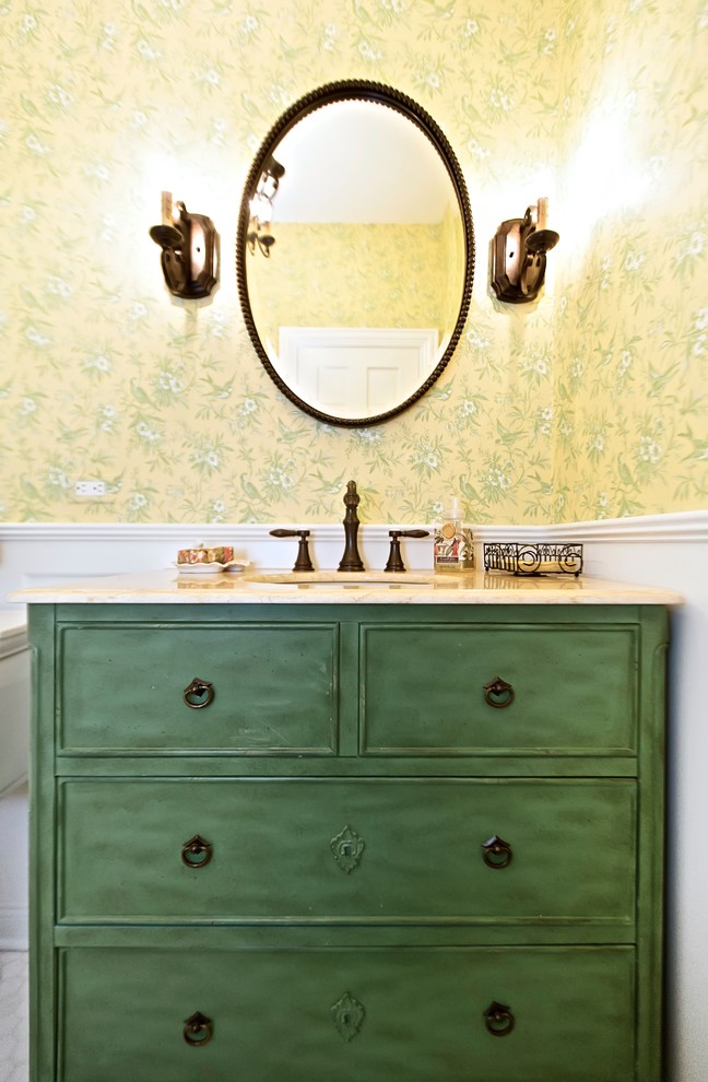Inredning av ett klassiskt litet toalett, med ett undermonterad handfat, möbel-liknande, gröna skåp, marmorbänkskiva och gula väggar