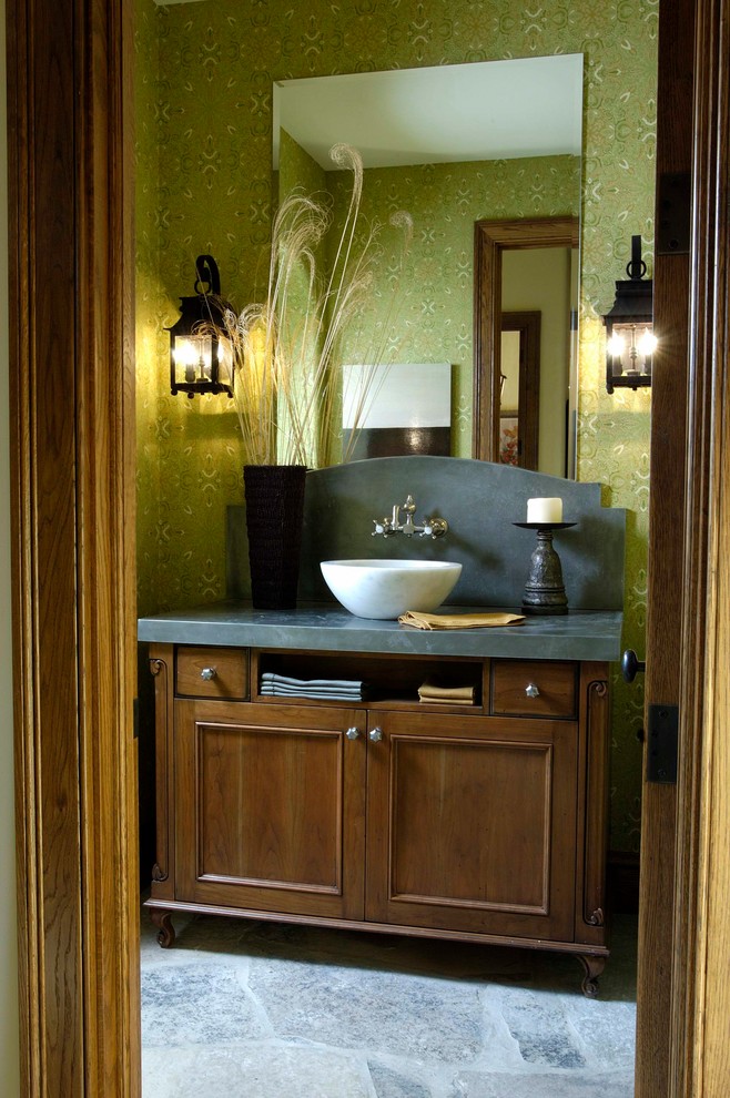 Klassisk inredning av ett mycket stort toalett, med luckor med infälld panel, skåp i mörkt trä, gröna väggar, ett fristående handfat och bänkskiva i täljsten