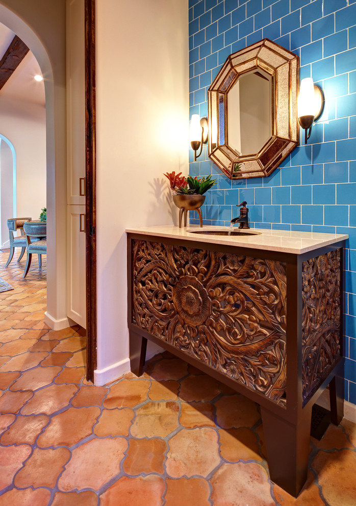 Kleine Mediterrane Gästetoilette mit Unterbauwaschbecken, verzierten Schränken, dunklen Holzschränken, blauen Fliesen, Keramikfliesen, Terrakottaboden und blauer Wandfarbe in Dallas