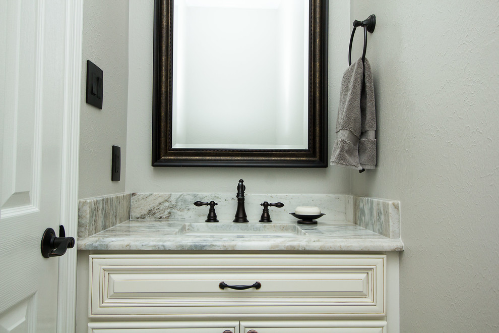 This is an example of a medium sized traditional cloakroom in Houston with raised-panel cabinets, white cabinets, grey walls, porcelain flooring, a submerged sink, granite worktops and grey floors.