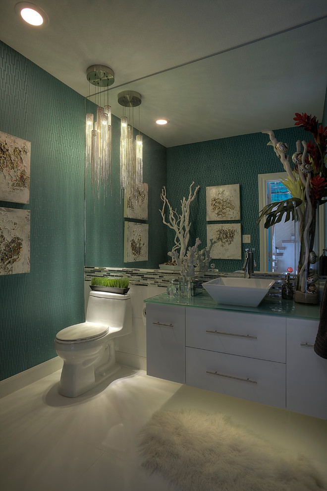 Moderne Gästetoilette mit Aufsatzwaschbecken, flächenbündigen Schrankfronten, weißen Schränken, Glaswaschbecken/Glaswaschtisch, Toilette mit Aufsatzspülkasten, weißen Fliesen, blauer Wandfarbe, Porzellan-Bodenfliesen und Stäbchenfliesen in Houston