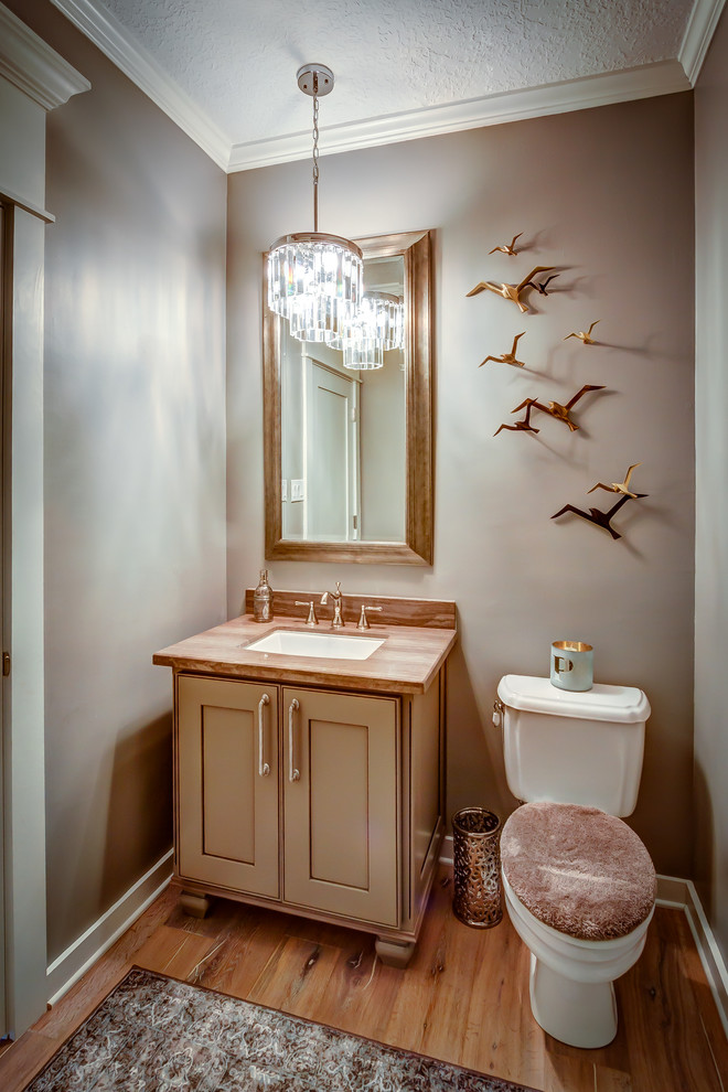 Cette image montre un petit WC et toilettes traditionnel avec un placard à porte affleurante, des portes de placard beiges, WC séparés, un mur gris, un sol en bois brun et un lavabo encastré.