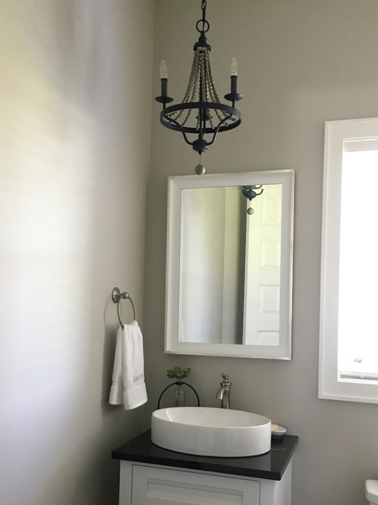 Cette image montre un petit WC et toilettes traditionnel avec un placard avec porte à panneau encastré, des portes de placard blanches, un mur gris, une vasque, un plan de toilette en surface solide et un plan de toilette noir.