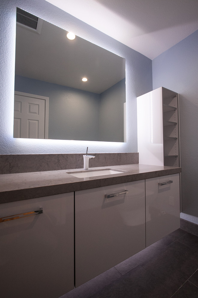 Exemple d'un petit WC et toilettes moderne avec un placard à porte plane, des portes de placard blanches, WC séparés, des carreaux de porcelaine, un mur bleu, un sol en carrelage de porcelaine, un lavabo encastré, un plan de toilette en quartz modifié et un sol gris.