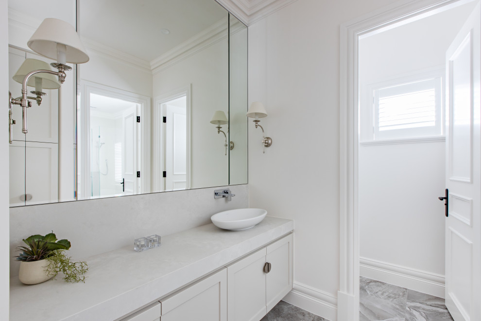 Inspiration for a timeless porcelain tile and gray floor powder room remodel in Adelaide with shaker cabinets, white cabinets, a one-piece toilet, white walls, a vessel sink, quartz countertops and white countertops