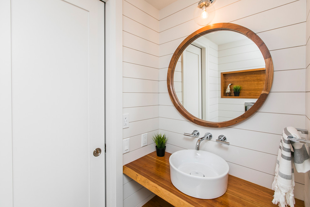 Small farmhouse cloakroom in Ottawa with a wall mounted toilet, white walls, light hardwood flooring, a vessel sink and wooden worktops.