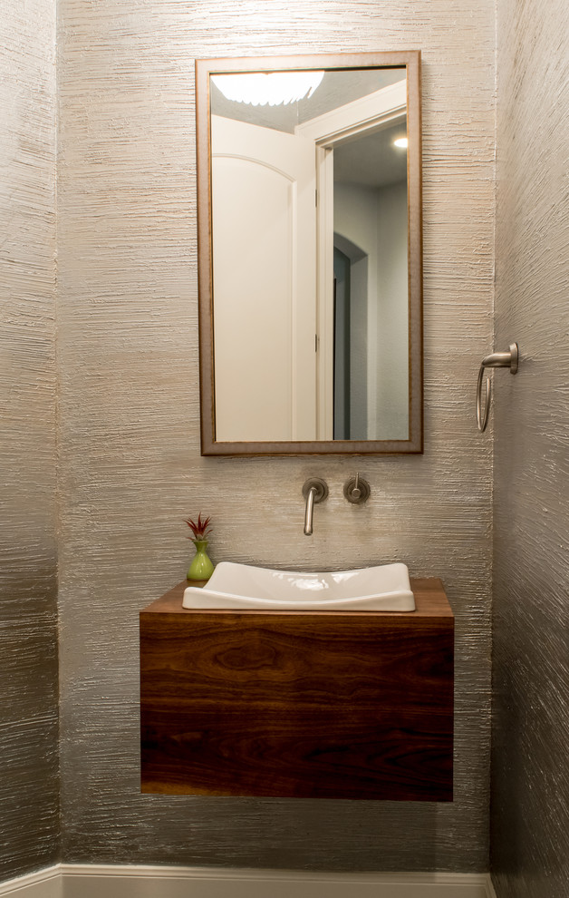 Inspiration for a small contemporary porcelain tile powder room remodel in Austin with wood countertops, a wall-mount toilet, a vessel sink, dark wood cabinets and brown countertops