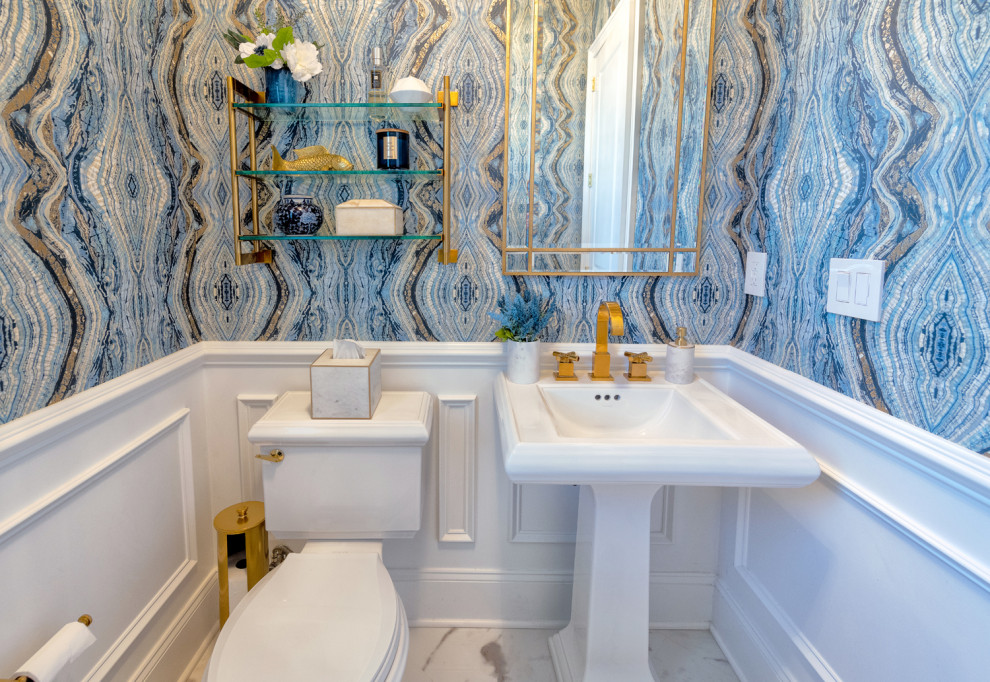 Photo of a large contemporary cloakroom in New York with white cabinets, a two-piece toilet, multi-coloured walls, marble flooring, a pedestal sink, white floors, a freestanding vanity unit and wallpapered walls.