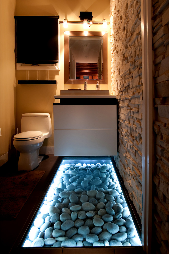 This is an example of a small modern cloakroom in New York with flat-panel cabinets, white cabinets, yellow walls, dark hardwood flooring, solid surface worktops, a one-piece toilet and a vessel sink.