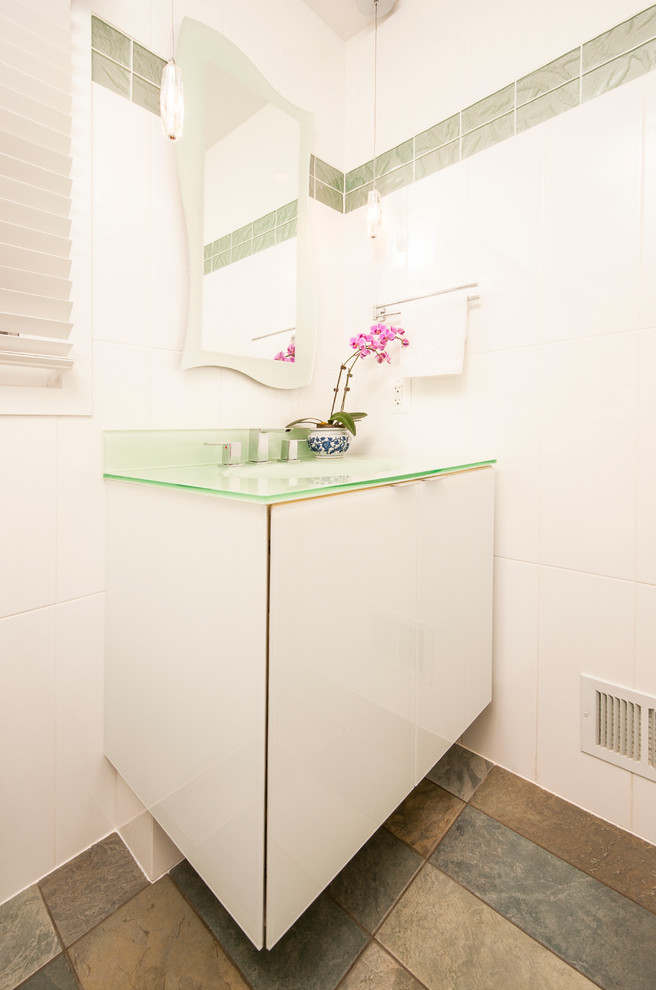 Стильный дизайн: маленький туалет в стиле модернизм с монолитной раковиной, стеклянными фасадами, белыми фасадами, стеклянной столешницей, белой плиткой, стеклянной плиткой и белыми стенами для на участке и в саду - последний тренд