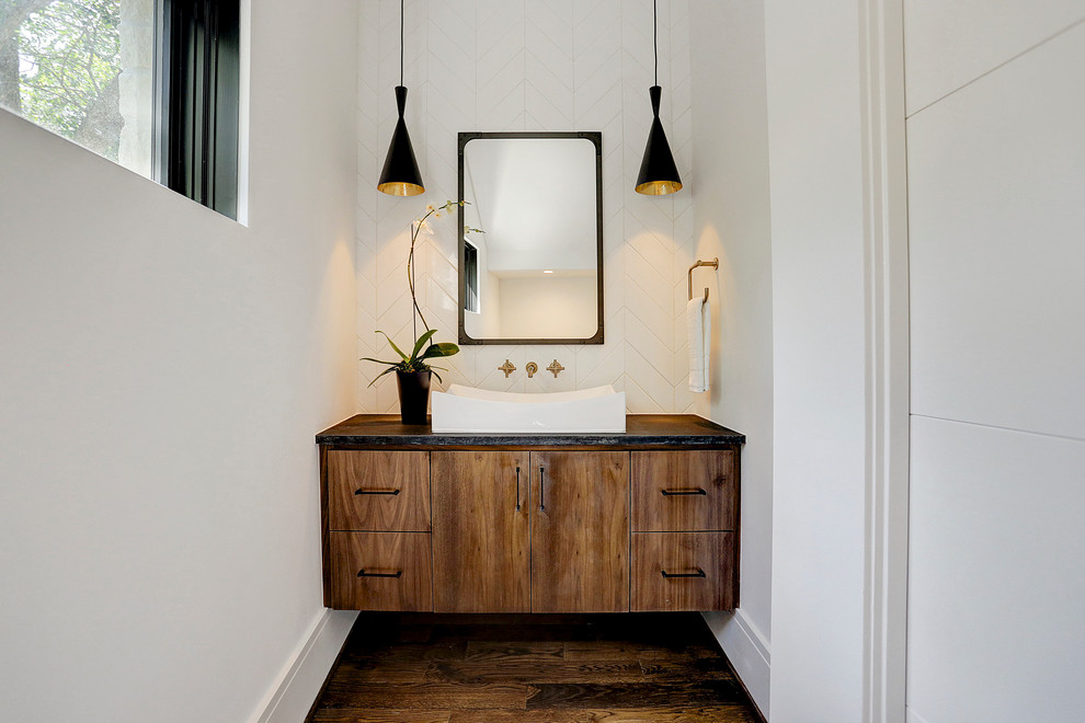 Inspiration for a mid-sized contemporary white tile and ceramic tile medium tone wood floor and brown floor powder room remodel with flat-panel cabinets, medium tone wood cabinets, a two-piece toilet, white walls, a console sink, granite countertops and black countertops