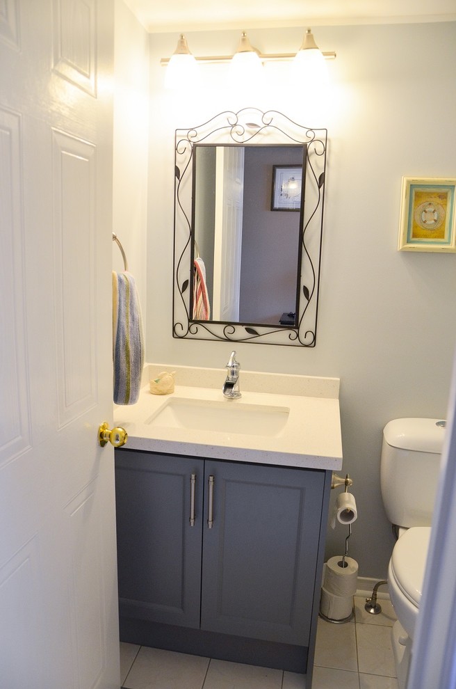 Photo of a small traditional cloakroom in Toronto with grey cabinets, a one-piece toilet, grey tiles, porcelain tiles, grey walls, porcelain flooring, a submerged sink, engineered stone worktops and recessed-panel cabinets.