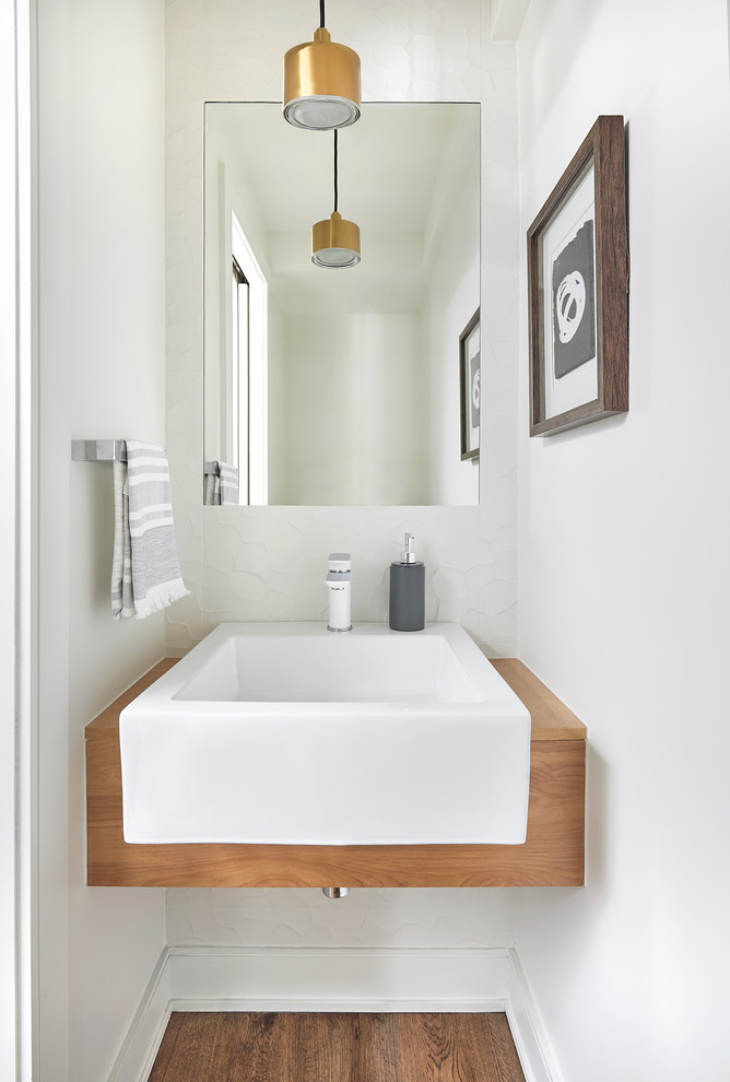 Réalisation d'un petit WC et toilettes design avec un sol en bois brun, un mur blanc, un lavabo suspendu et un plan de toilette en bois.