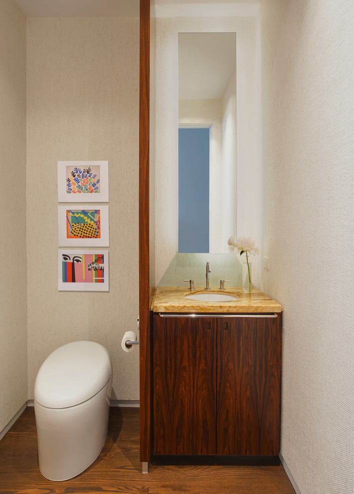 Inspiration pour un WC et toilettes design en bois brun avec un placard à porte plane, WC à poser, un mur beige, un sol en bois brun, un lavabo encastré et un sol marron.