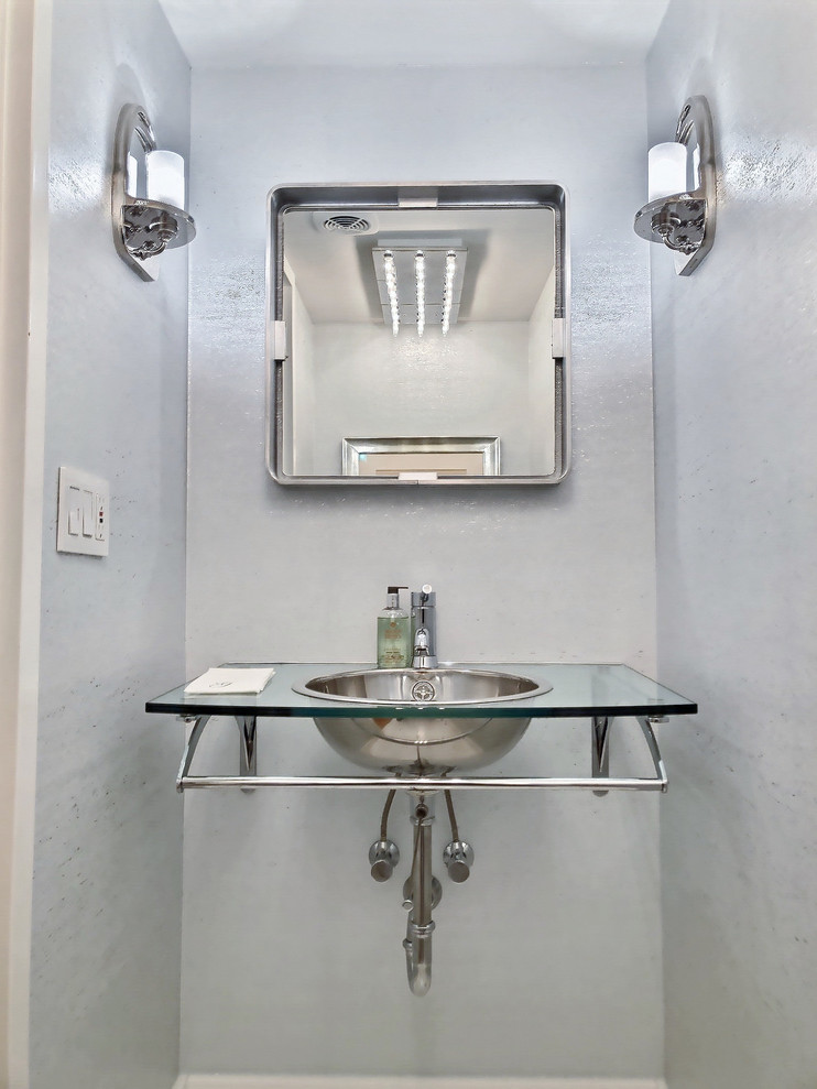 Imagen de aseo minimalista pequeño con encimera de vidrio, paredes blancas y lavabo suspendido