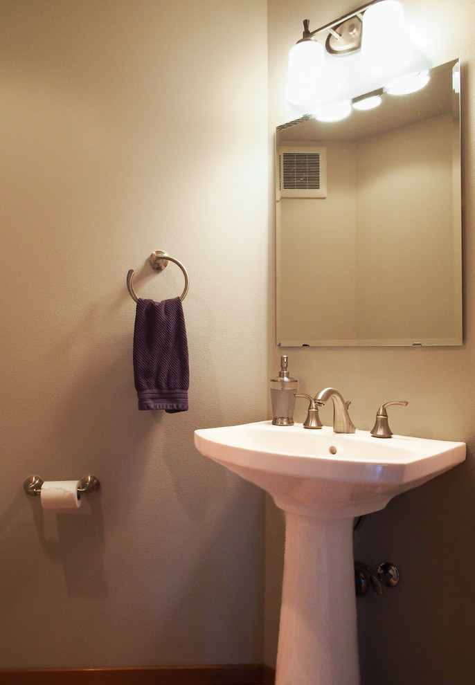 Ispirazione per un bagno di servizio tradizionale di medie dimensioni con lavabo a colonna, WC a due pezzi, pareti beige, parquet chiaro e pavimento marrone