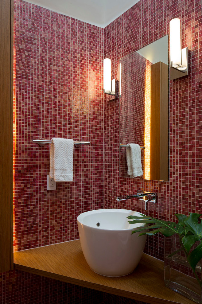 На фото: туалет в современном стиле с столешницей из дерева, плиткой мозаикой, настольной раковиной и розовой плиткой