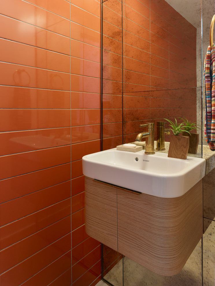 Bild på ett litet 50 tals toalett, med möbel-liknande, skåp i mellenmörkt trä, en toalettstol med separat cisternkåpa, orange kakel, keramikplattor, ett väggmonterat handfat och bänkskiva i glas