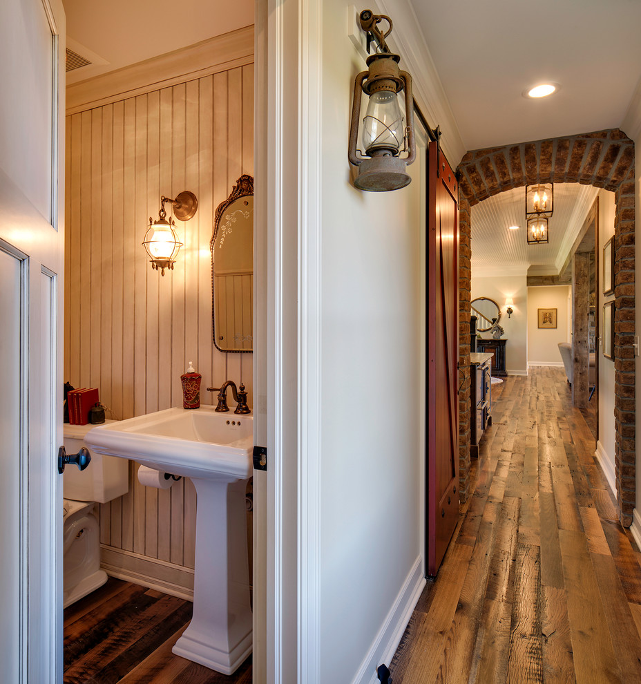 Kleine Landhausstil Gästetoilette mit Wandtoilette mit Spülkasten, braunem Holzboden und Sockelwaschbecken in Minneapolis