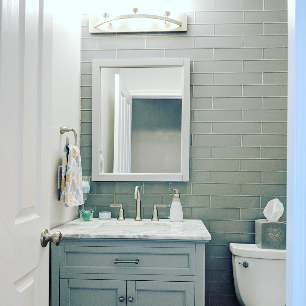 Пример оригинального дизайна: маленький туалет в современном стиле с плоскими фасадами, серыми фасадами, раздельным унитазом, синей плиткой, стеклянной плиткой, серыми стенами, полом из ламината, врезной раковиной, мраморной столешницей, серым полом и белой столешницей для на участке и в саду