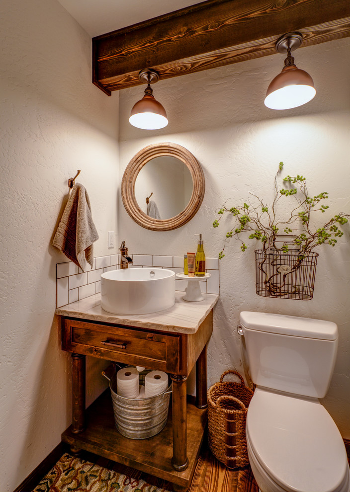 Cette image montre un WC et toilettes chalet en bois brun avec une vasque, un placard à porte shaker, un plan de toilette en quartz, WC séparés, un carrelage blanc, un carrelage métro, un mur blanc, un sol en bois brun et un plan de toilette beige.