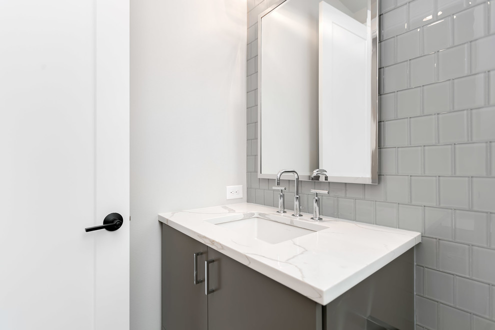 Стильный дизайн: туалет среднего размера в современном стиле с плоскими фасадами, серыми фасадами, серой плиткой, стеклянной плиткой, серыми стенами, врезной раковиной, столешницей из искусственного кварца и белой столешницей - последний тренд