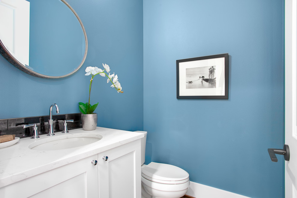 Ispirazione per un bagno di servizio american style di medie dimensioni con ante con riquadro incassato, ante bianche, WC a due pezzi, piastrelle nere, pareti blu, lavabo sottopiano, top in quarzo composito e top bianco