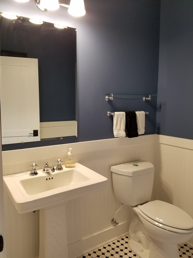 Bild på ett litet vintage toalett, med en toalettstol med separat cisternkåpa, svart och vit kakel, keramikplattor, blå väggar, mosaikgolv, ett piedestal handfat, bänkskiva i akrylsten och flerfärgat golv