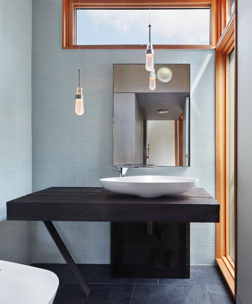 Design ideas for a small contemporary cloakroom in Minneapolis with a bidet, blue tiles, glass tiles, blue walls, slate flooring, a vessel sink, wooden worktops, black floors, open cabinets, dark wood cabinets and brown worktops.