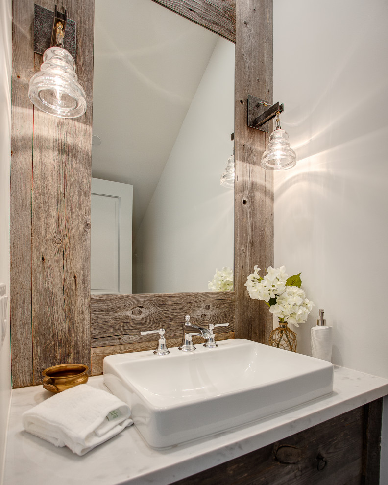 Exempel på ett litet lantligt vit vitt toalett, med släta luckor, skåp i slitet trä, en toalettstol med hel cisternkåpa, grå väggar, mellanmörkt trägolv, ett fristående handfat, marmorbänkskiva och brunt golv