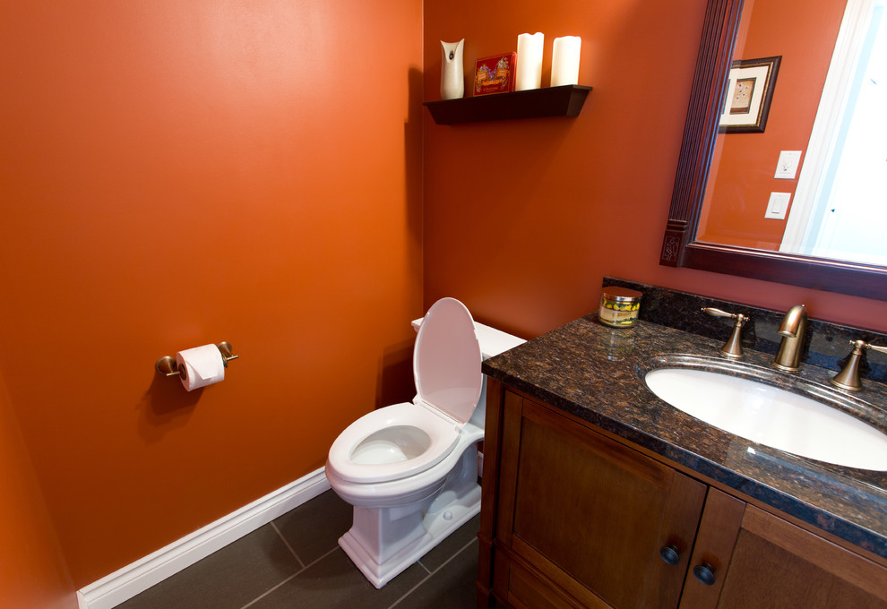 Inspiration for a small transitional slate floor powder room remodel in Toronto with recessed-panel cabinets, medium tone wood cabinets, a two-piece toilet, orange walls, an undermount sink and granite countertops