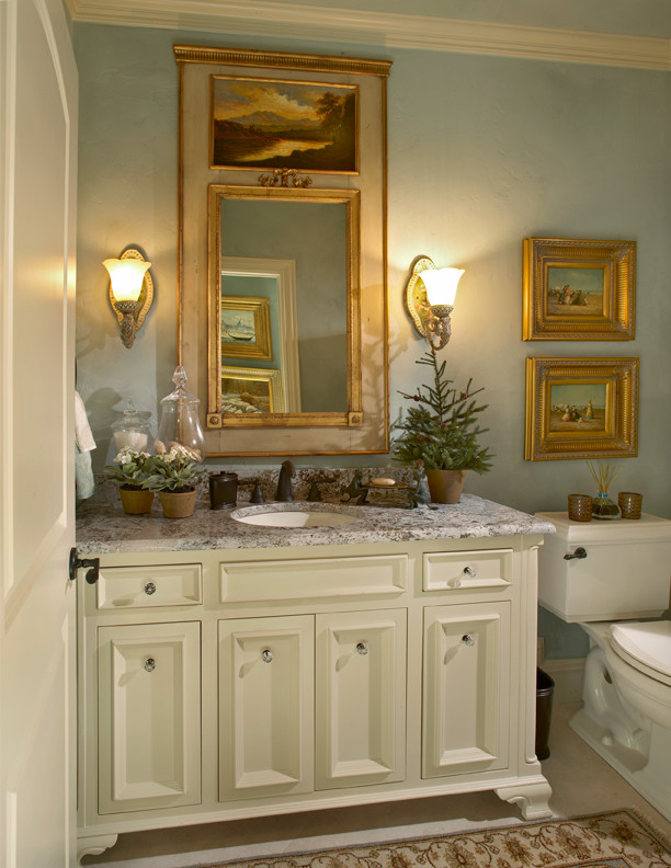 Cette photo montre un WC et toilettes chic de taille moyenne avec un lavabo encastré, un placard à porte affleurante, un plan de toilette en granite, WC séparés, un carrelage beige, un mur bleu et des portes de placard beiges.