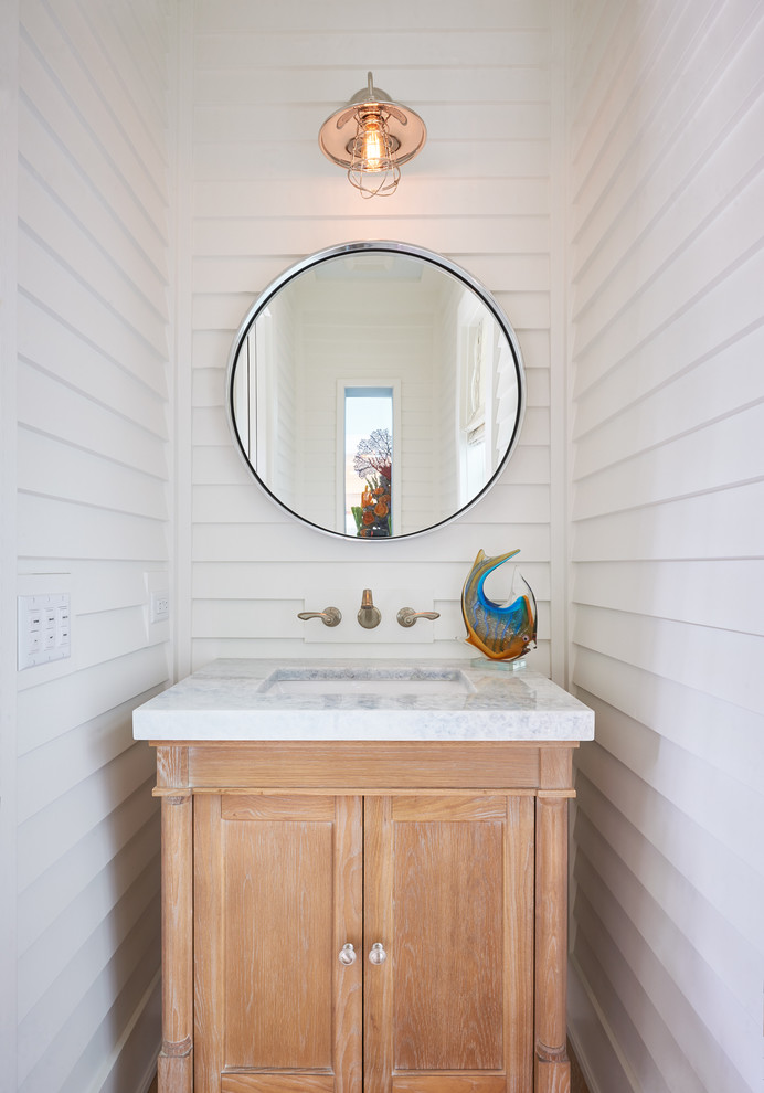 Cette image montre un petit WC et toilettes traditionnel en bois clair avec un lavabo encastré, un placard en trompe-l'oeil, un mur blanc et un plan de toilette en granite.