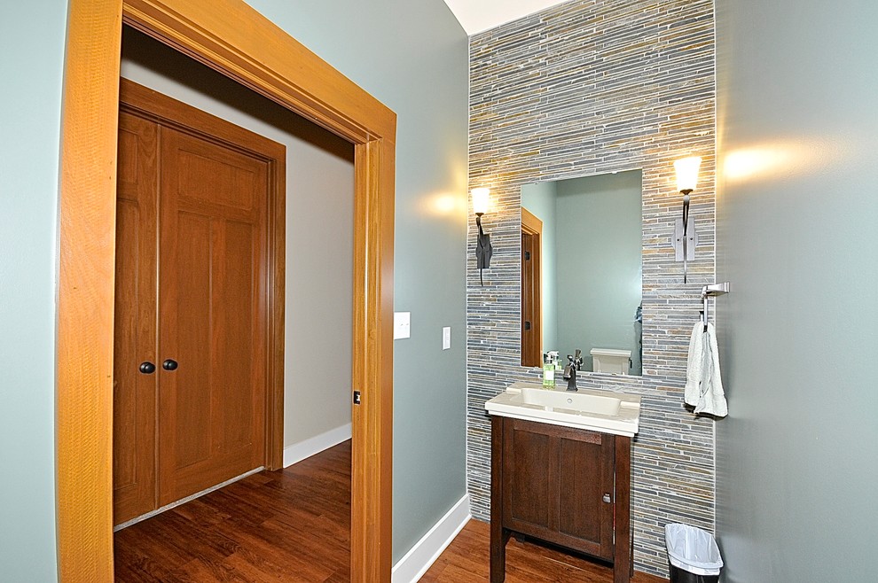 Example of a transitional multicolored tile and travertine tile medium tone wood floor powder room design in Indianapolis with an integrated sink, furniture-like cabinets, dark wood cabinets, a two-piece toilet and green walls