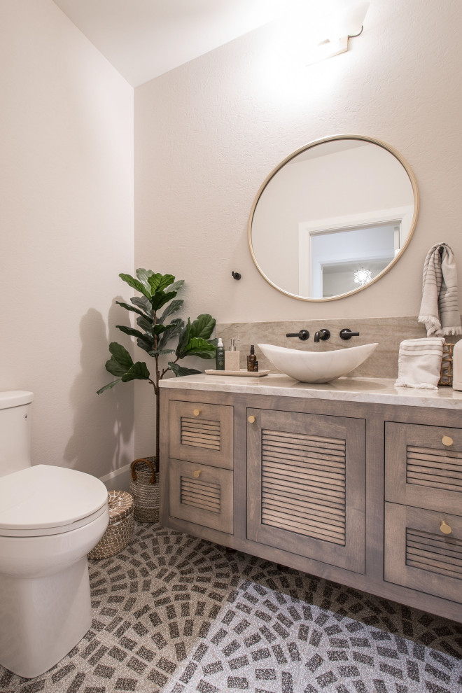 Klassisk inredning av ett toalett, med terrazzogolv, beiget golv, luckor med lamellpanel, bruna skåp, en toalettstol med separat cisternkåpa, vita väggar och ett fristående handfat