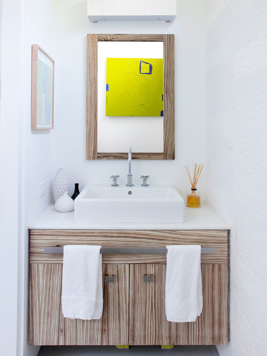 Mid-sized trendy concrete floor powder room photo in New York with flat-panel cabinets, light wood cabinets, white walls, a vessel sink, limestone countertops and white countertops