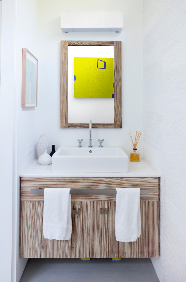 Idées déco pour un WC et toilettes contemporain en bois clair de taille moyenne avec un mur blanc, sol en béton ciré, un plan de toilette en calcaire, une vasque, un placard à porte plane et un plan de toilette blanc.
