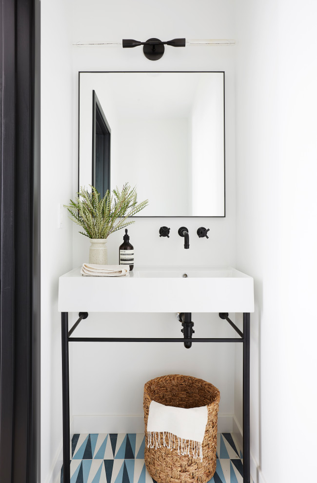 Small contemporary cloakroom in Los Angeles with open cabinets, cement flooring, blue floors, white walls and a console sink.