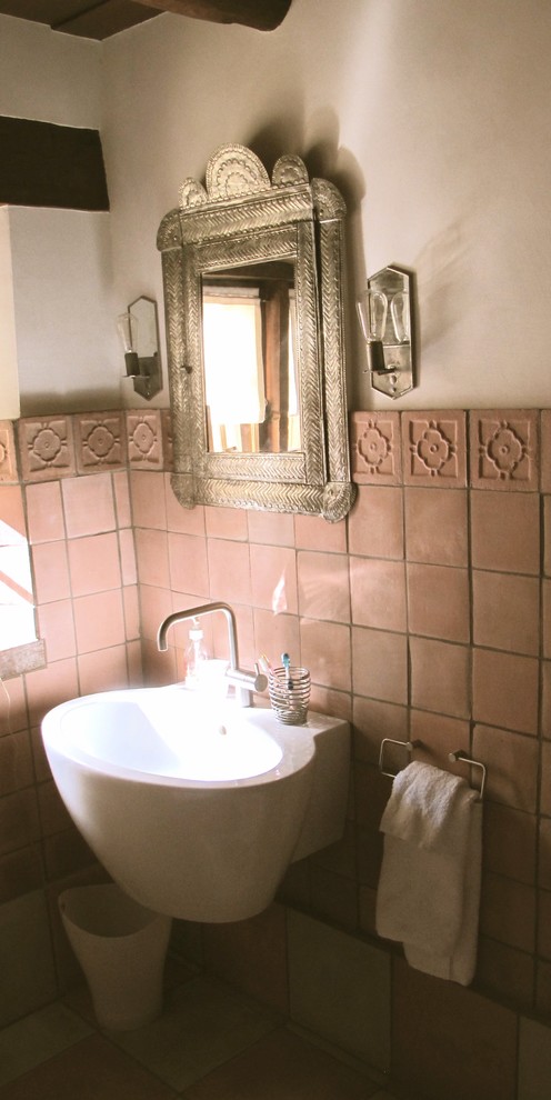 Bild på ett litet amerikanskt toalett, med perrakottakakel, beige väggar, klinkergolv i terrakotta, ett väggmonterat handfat och beiget golv