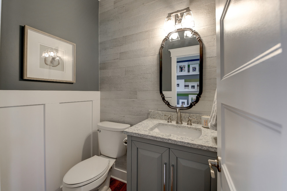 Small traditional cloakroom in Dallas with raised-panel cabinets, grey cabinets, a two-piece toilet, grey walls, medium hardwood flooring, a submerged sink, granite worktops, brown floors and grey worktops.