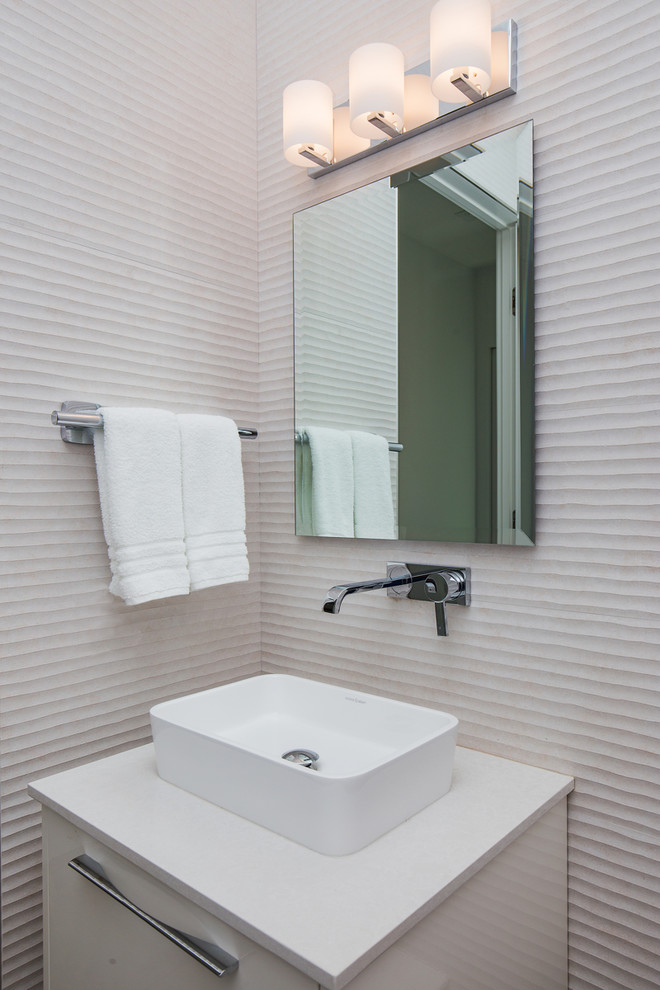 Inredning av ett modernt mellanstort toalett, med släta luckor, vita skåp, porslinskakel, klinkergolv i porslin, ett fristående handfat, bänkskiva i kvarts, vit kakel, vita väggar, grått golv och en vägghängd toalettstol