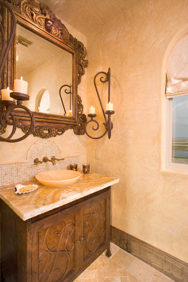 Idées déco pour un petit WC et toilettes méditerranéen en bois brun avec un placard en trompe-l'oeil, un plan de toilette en onyx, un carrelage beige, WC à poser, une vasque, un mur beige, un sol en travertin, mosaïque et un plan de toilette beige.