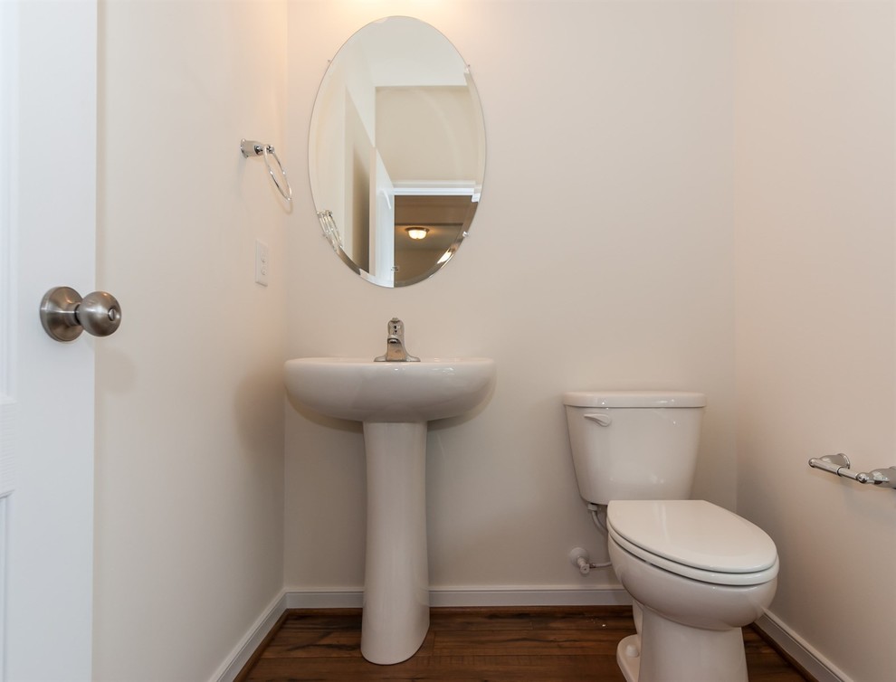 Immagine di un piccolo bagno di servizio tradizionale con WC a due pezzi, pareti beige, pavimento in legno massello medio e lavabo a colonna