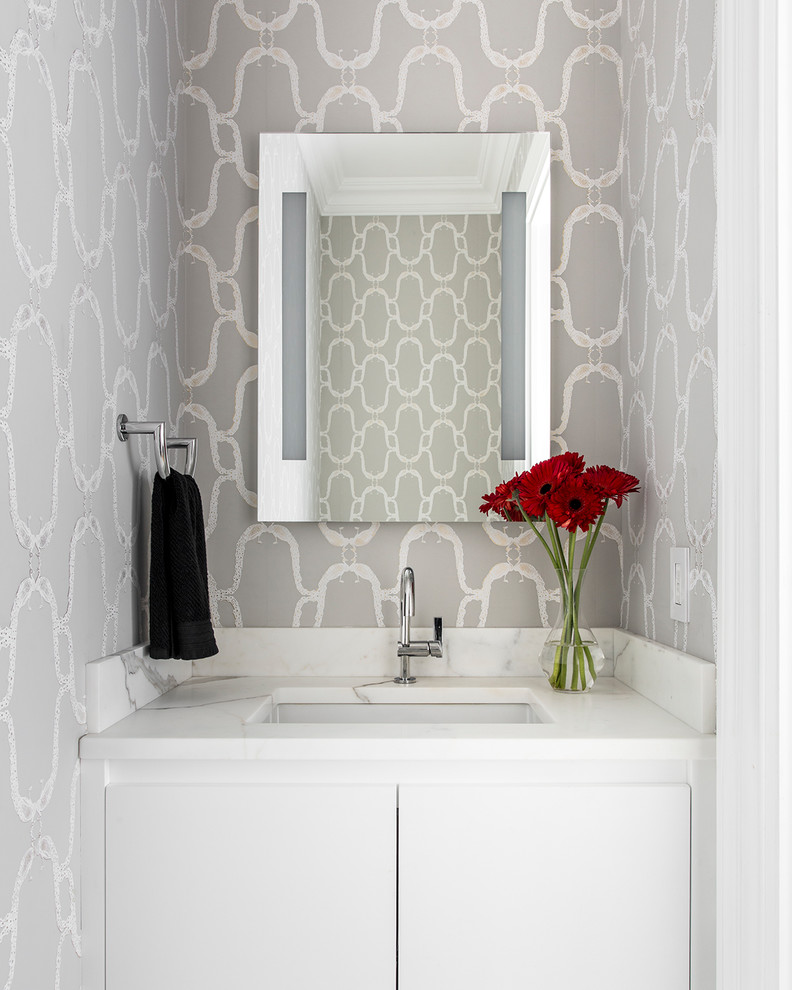 Inspiration pour un petit WC et toilettes minimaliste avec un placard à porte plane, des portes de placard blanches, un mur gris, un lavabo encastré et un plan de toilette en marbre.