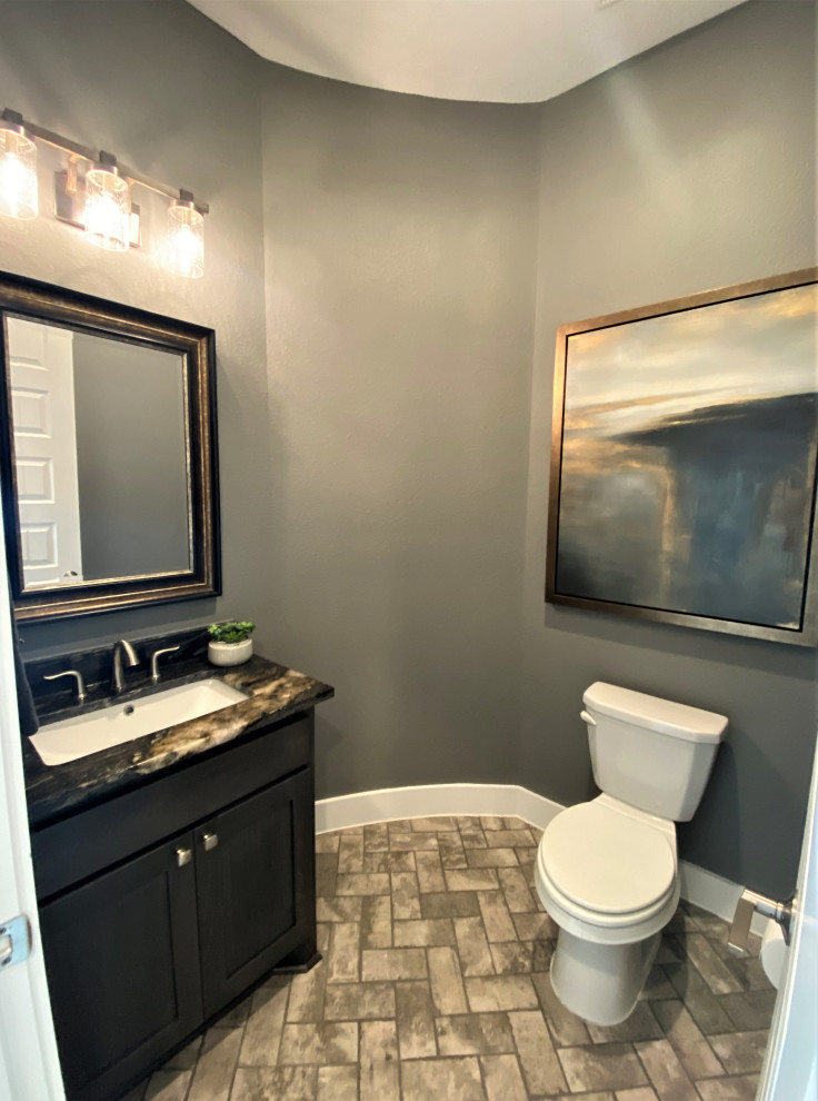 Cette image montre un WC et toilettes traditionnel en bois foncé de taille moyenne avec un placard à porte shaker, un mur gris, un sol en carrelage de porcelaine, un lavabo encastré, un plan de toilette en granite, un sol gris, un plan de toilette noir et meuble-lavabo encastré.