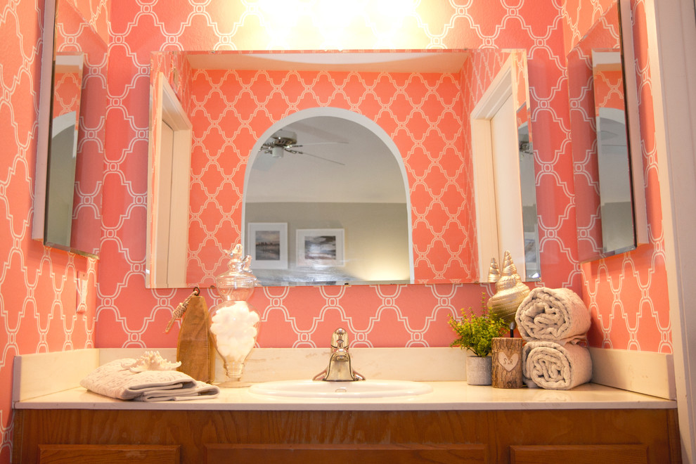 Свежая идея для дизайна: туалет в морском стиле с накладной раковиной, столешницей из искусственного камня, розовыми стенами и фасадами цвета дерева среднего тона - отличное фото интерьера