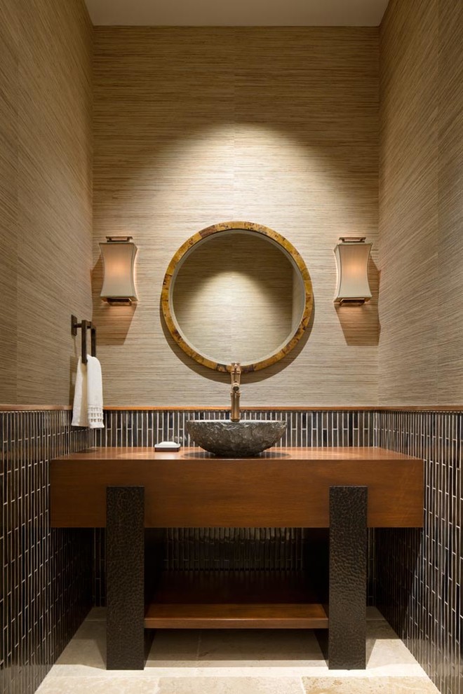 Contemporary cloakroom in Miami with open cabinets, medium wood cabinets, brown tiles, matchstick tiles, brown walls, a vessel sink and beige floors.
