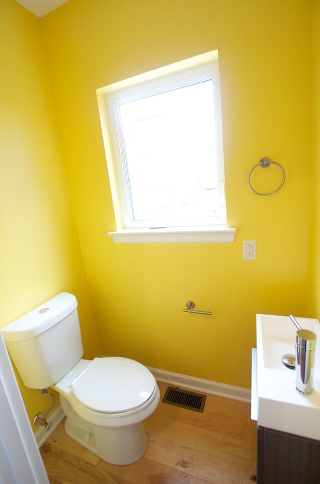 Источник вдохновения для домашнего уюта: туалет в скандинавском стиле с монолитной раковиной, плоскими фасадами, темными деревянными фасадами, раздельным унитазом, желтыми стенами и паркетным полом среднего тона