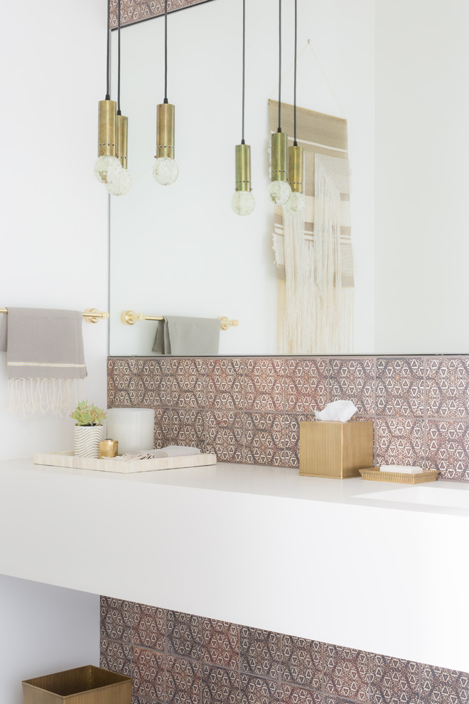 Esempio di un bagno di servizio design con piastrelle marroni, pareti bianche, lavabo integrato e top bianco